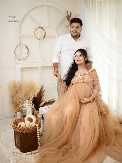 A full-length portrait of the couple in a beautiful boho setting. The mother-to-be's flowing gown and the rustic props create a picture of natural elegance.