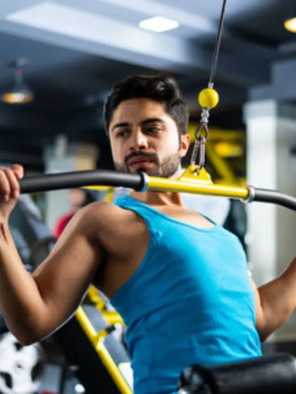 A client using the lat pulldown machine. This is a key exercise for developing a wide back and achieving that V-taper look.