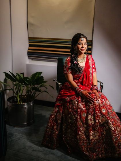 A radiant bride ready for her Sangeet night in a stunning red lehenga. The makeup is glamorous and festive, perfect for a night of celebration.
