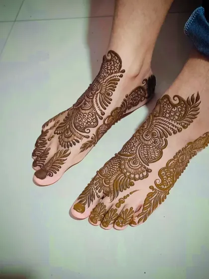 An intricate Arabic-style foot mehandi that flows beautifully along the side of the foot, adorned with paisleys and leafy vines.