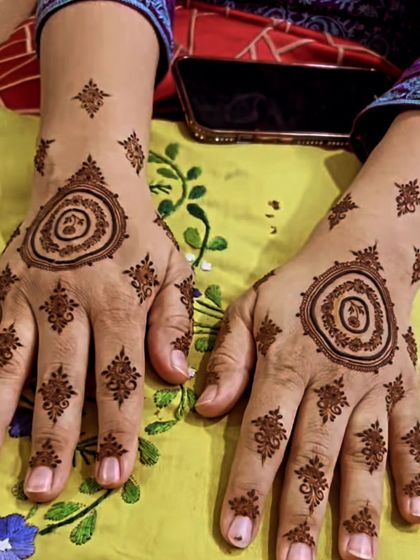 A matching set of designer mandalas for both hands. The central circular pattern is surrounded by delicate motifs, creating a symmetrical and modern mehendi style.