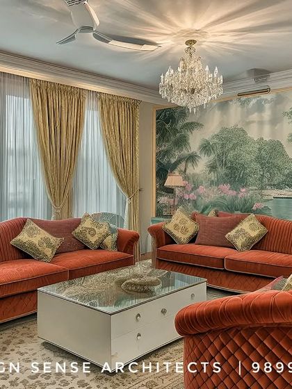 A classically designed living room in Janakpuri, featuring plush red sofas, a crystal chandelier, and a stunning hand-painted landscape mural that serves as a serene backdrop.