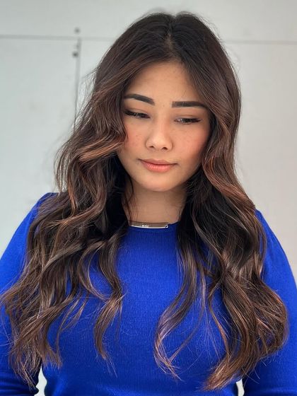 A warm brown brunette look, styled with soft waves. The color is rich and inviting, perfect for any season.