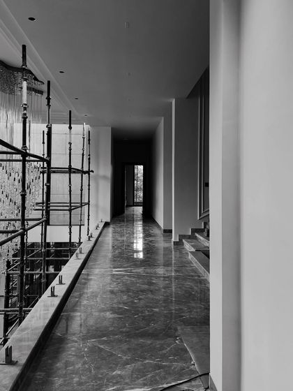 A corridor during construction, with the marble flooring laid but scaffolding still in place for the chandelier installation, showing the phased process of finishing.