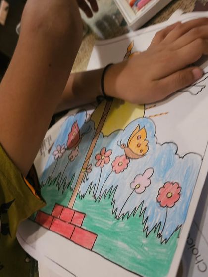 A close-up of a student coloring the garden scene around the Indian flag for their Independence Day project.