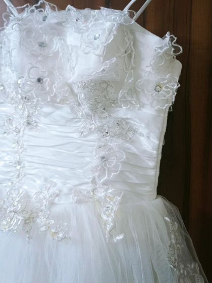 A detailed look at the front of the white corset gown. The ruffled neckline and intricate floral beading make this a truly special rental piece.