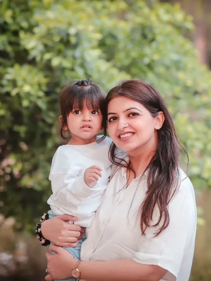 A mother holds her daughter in a beautiful outdoor setting. We use natural light to create soft, flattering family portraits.