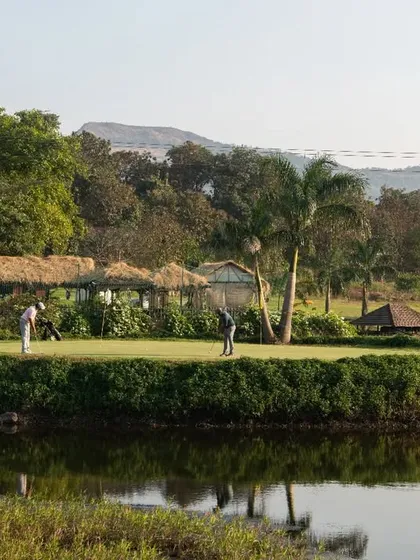 Golf is best enjoyed with friends. This view shows a group of players on one of our greens, surrounded by water and our thatched-roof rest areas, highlighting the social and scenic aspects of a day at our course.