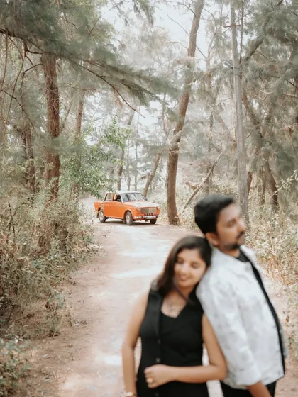 A quiet, romantic moment between the couple, with the vintage car in the background setting a nostalgic scene in the woods.