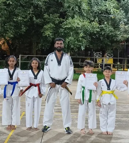 Students of different ages posing with their certificates after a belt grading exam held outdoors. We celebrate every student's progress, no matter their age or level.
