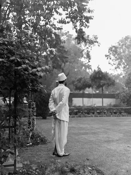 A quiet, contemplative black and white shot for Sanchit Sharma. The image captures a model from behind in a garden setting, creating a sense of narrative and mystery.