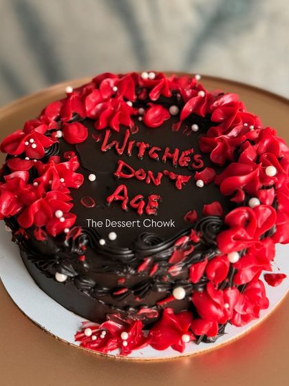 A fun and witchy cake for a friend's birthday with the message "Witches Don't Age." This dark chocolate truffle cake has a bold red and black design.