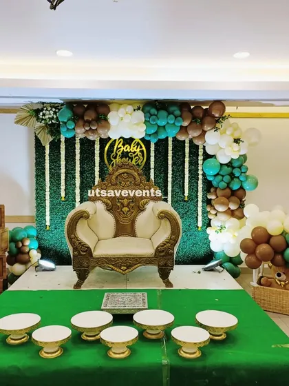 I also create modern fusion designs that blend contemporary aesthetics with traditional functions. This baby shower setup features a stylish balloon arch in earthy tones, a green foliage wall, and classic wooden 'BABY' blocks, all while keeping the traditional plate ceremony at the forefront.