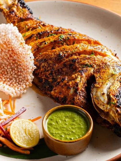 A whole tandoori fish, beautifully charred and spiced. Served with a side of green chutney and salad, it's a showstopper of a main course.