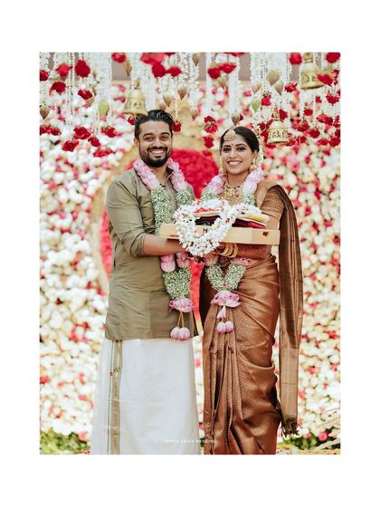 A happy portrait of the couple holding a tray of offerings, a moment from their traditional Hindu ceremony.