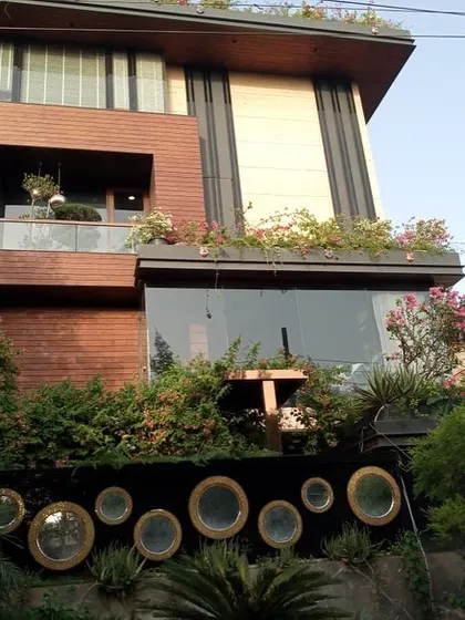 Another angle of the impressive Noida residence, highlighting the integration of the lush, complex garden with the home's modern wood and glass exterior.