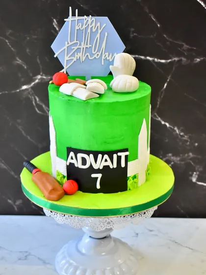 The full view of the cricket-themed cake, featuring a vibrant green pitch, a scoreboard with the birthday boy's name, and edible cricket equipment.