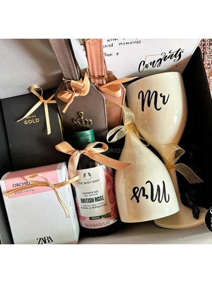A sophisticated couple's hamper featuring 'Mr & Mrs' wine glasses, personalized luggage tags, and luxury bath products from The Body Shop and Zara.