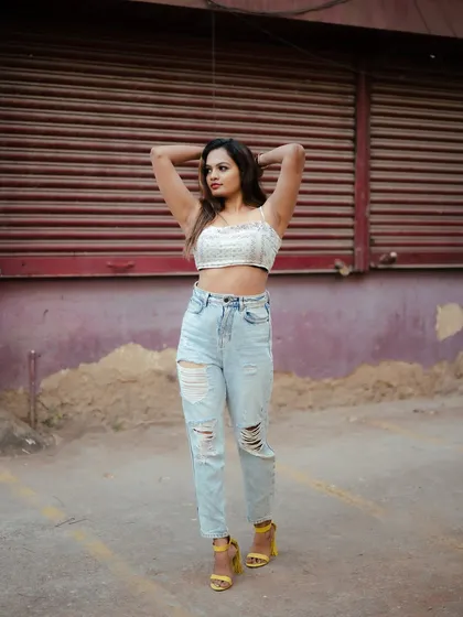 A full-length street style shot. The model's casual outfit and confident pose against the urban backdrop create a relatable and fashionable portrait.
