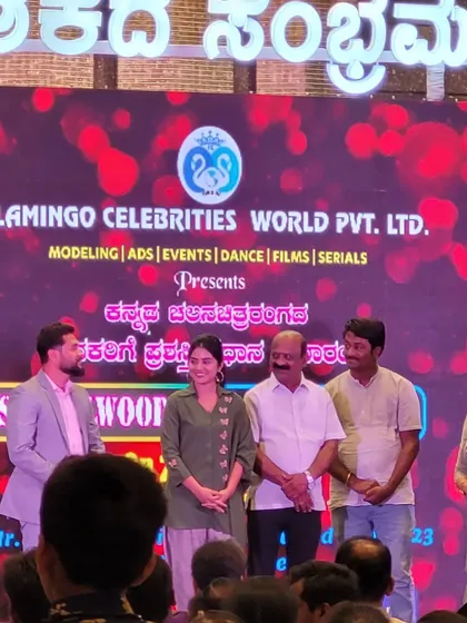 A group of artists and presenters on stage at the "Sandalwood Stars Night". The large LED screen in the background provides a vibrant and professional backdrop for all photo opportunities.