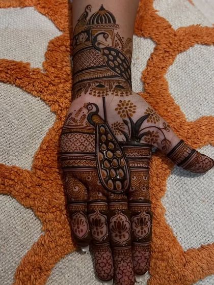 A single hand from a trial session, focusing on a large, elegant peacock as the central element, complemented by floral patterns on the fingers.