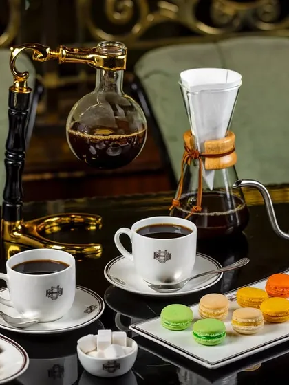 A coffee connoisseur's spread with a siphon, french press, and pour-over coffee maker, styled with macarons and cookies for United Coffee House.