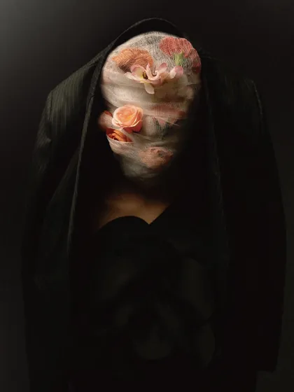 A darker, more mysterious version of the flower-wrapped face concept. The low-key lighting almost completely obscures the form, leaving only a hint of the flowers and the shape of the jacket.