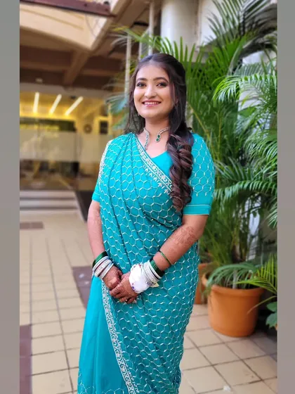 A smiling bride-to-be at her engagement, looking lovely in a turquoise saree styled in a modern mermaid drape.