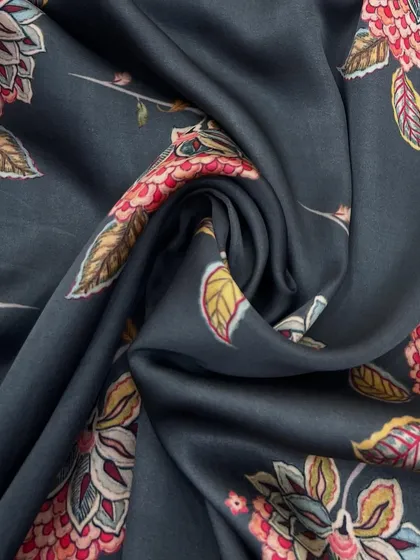This printed modal fabric features a rich, kalamkari-inspired floral design on a deep charcoal base. Its effortless gloss makes it a beautiful choice for a gown or anarkali.