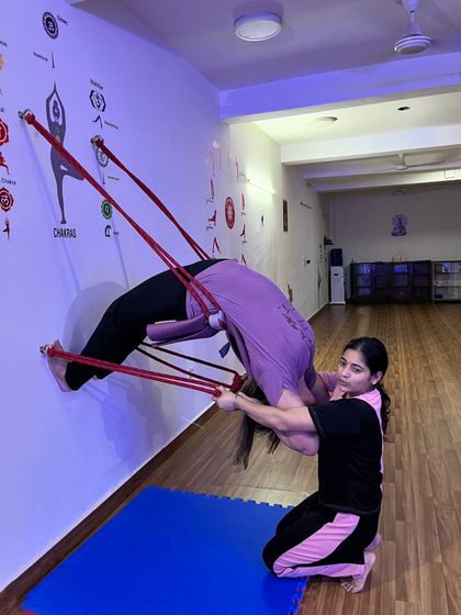 Assisting a student in a very deep backbend using the wall ropes. My role is to ensure they are safe while they explore their limits.