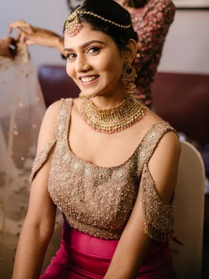 A happy, smiling shot of the bride in the makeup chair. Her radiant glow is a testament to the magic of a flawless base and well-placed highlighter.