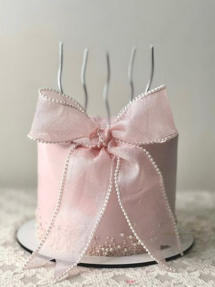 A pretty pink cake featuring our signature ribbon bow. The simplicity of the design, with the large, perfectly crafted bow, makes it a client favorite.