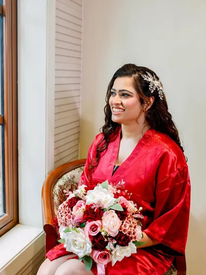 The beauty of the moment before the vows. Our bride is happy and relaxed in her red robe, holding her bouquet, ready for her big day.