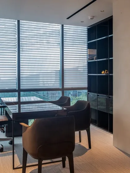 The director’s cabin in this Gurugram office is a study in bespoke detail. We custom-designed the furniture, pairing a rich wood table with plush chairs to create a workspace that feels timeless and tactile. The darker palette contrasts with the room's natural light, achieving a perfect balance.