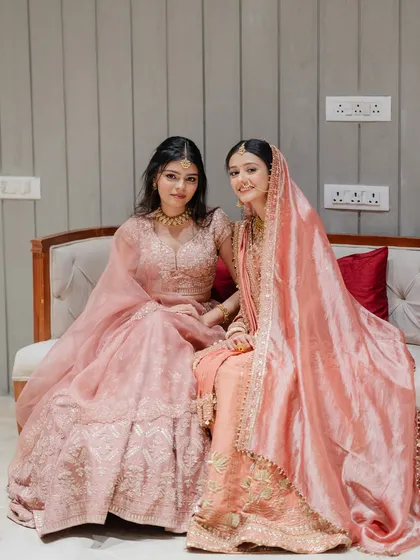 The bride and her sister sharing a quiet moment before the ceremony. Their coordinated pastel lehengas create a soft, dreamy aesthetic perfect for a modern wedding.