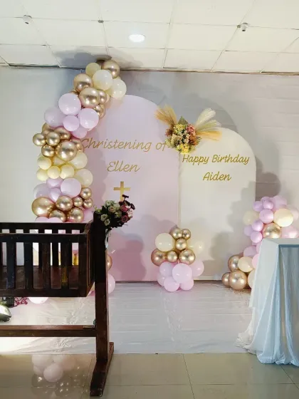A wider view of the Christening and birthday setup. The decor includes a traditional wooden cradle, making it suitable for a religious ceremony while still feeling celebratory.