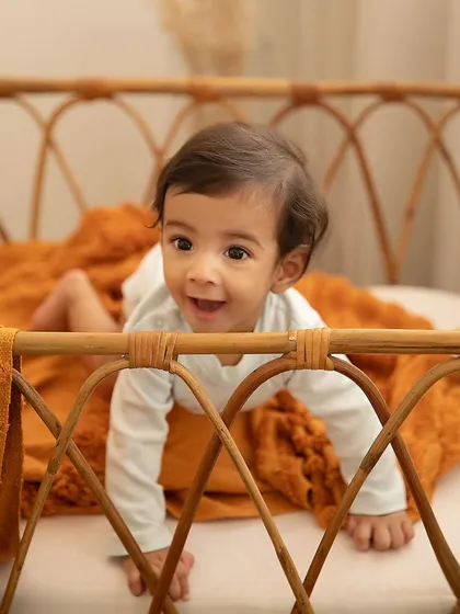 Peeking over the side of this beautiful cane bassinet, this little one's happy expression is priceless. My studio has a variety of props to create different looks for your session.