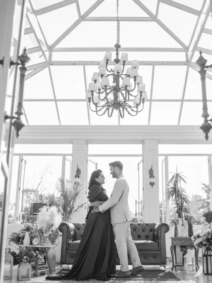 A classic black and white portrait of the couple in a grand conservatory. The timeless monochrome effect emphasizes their elegant poses and the stunning architecture.