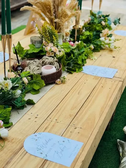 We designed a low-seating picnic-style table for a relaxed and intimate boho baby shower. The wooden table is adorned with a green garland and personalized place cards.