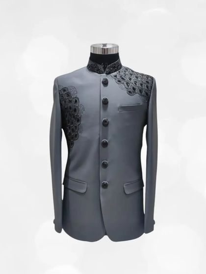 This grey Jodhpuri suit features unique black peacock-feather style embroidery on the shoulders. It's a distinctive piece for those who appreciate fine detailing.
