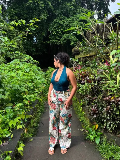 Saying goodbye to summer 2025. A full shot of the floral pants and teal halter top in a beautiful garden setting in Bali. This outfit is all about embracing nature and color.