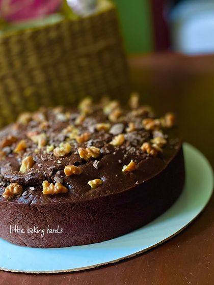 A side view of the dark chocolate, walnut, and date cake, showing its lovely height and the generous topping of crunchy walnuts.