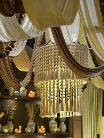 We love creating unique ambiances with texture and light. This ceiling treatment combines flowing, earthy-toned fabrics with a stunning tassel chandelier, achieving a look of rustic, bohemian elegance for a chic and relaxed event.