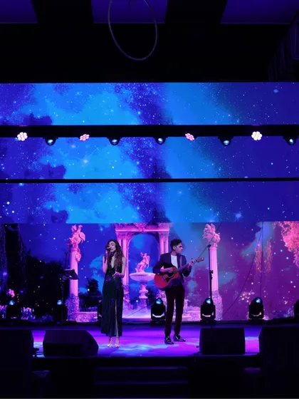 A live musical duo performing on stage against a celestial-themed LED backdrop, creating a romantic and soulful ambiance.