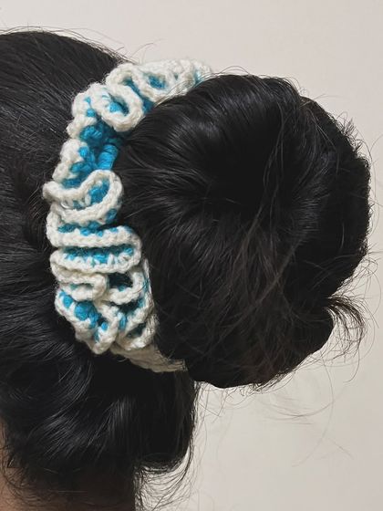 A blue and white ruffled hairtie, shown here styled around a hair bun.