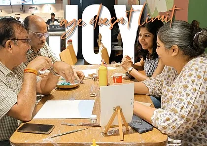 Age doesn't limit joy. Here, two fathers in their 70s are fully engaged in the painting process, brought to the workshop by their loving daughters.
