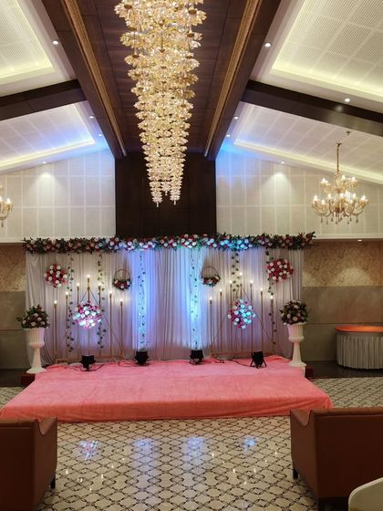 A wide-angle view of the banquet hall, showing the full scale of the event space with the decorated stage at the far end.
