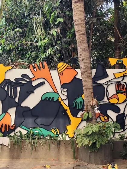 Another view of the outdoor metal art, showing how the vibrant colors pop against the white wall and green landscape.