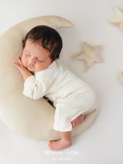 A dreamy, celestial-themed shot with a baby on a moon prop, demonstrating how to create whimsical and imaginative setups.