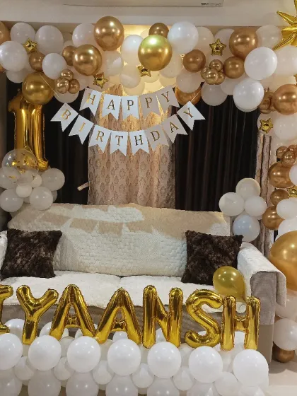 A grand living room decoration for a first birthday. I framed the sofa with a white and gold balloon arch and added the name in foil letters at the bottom, transforming the space for the celebration.